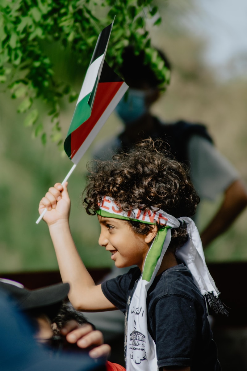boy in blue and white shirt holding flag of us a during daytime