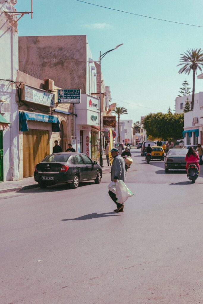 man in white shirt walking on sidewalk during daytime